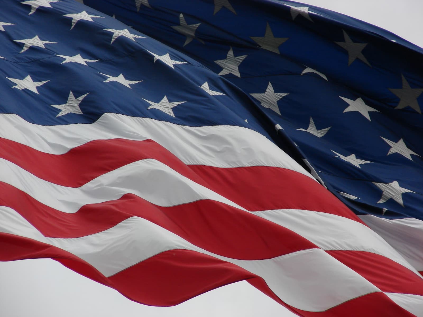 The image depicts the American flag, featuring red and white stripes with a blue field containing white stars.